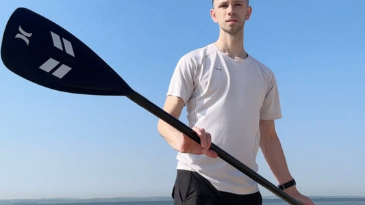 Adam Feast holding Black Paddle Board Paddle at Lee on Solent beach with the sea behind him