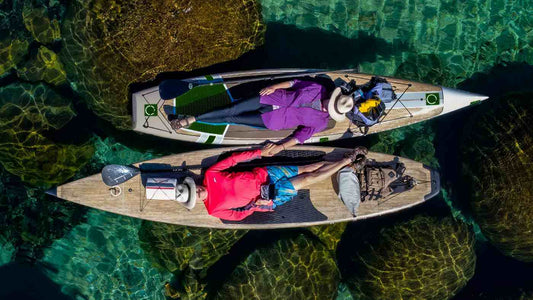 Two people lying down on their Paddle Boards floating on the sea