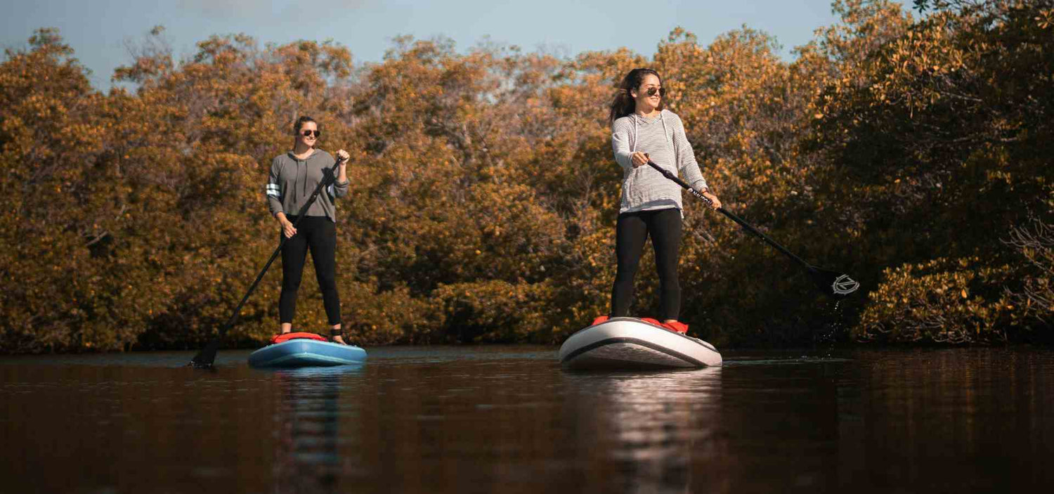 Two women Paddle Boarding with sunglasses on.